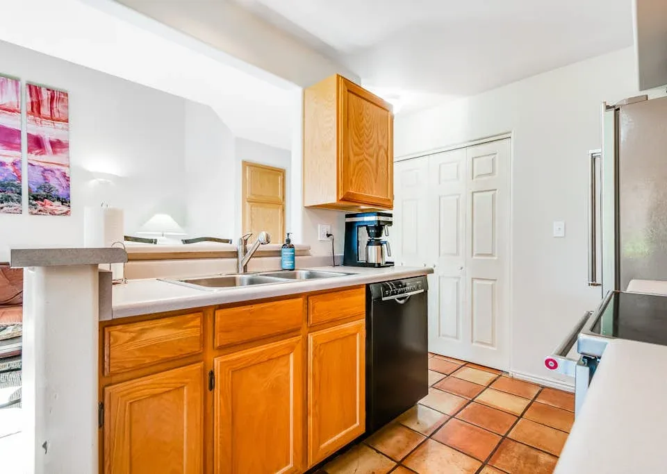 A compact kitchen with wooden cabinets, a countertop, and a black dishwasher.