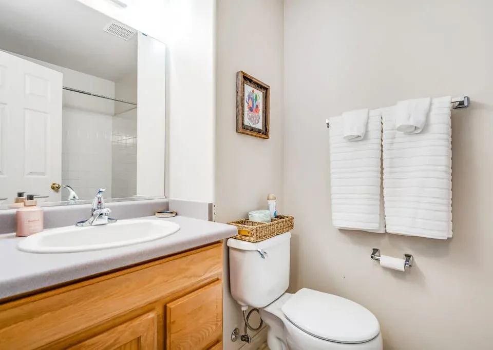 A bathroom with a sink, toilet, and neatly folded towels on the wall.
