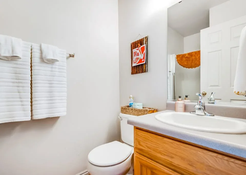 A bathroom with a sink, toilet, and white towels hanging on the wall.