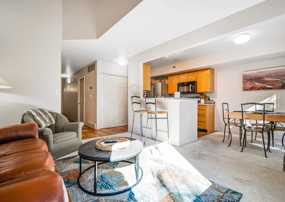 An open-plan living area with seating, a kitchen island, and a dining table.