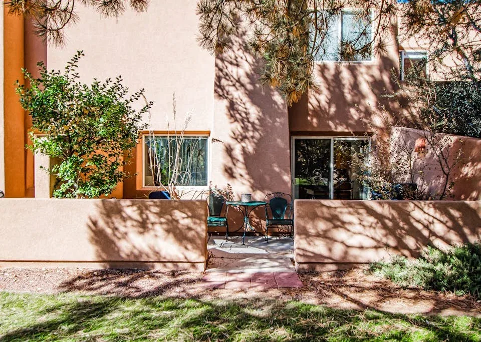 A pink stucco building with a patio seating area and trees in front.