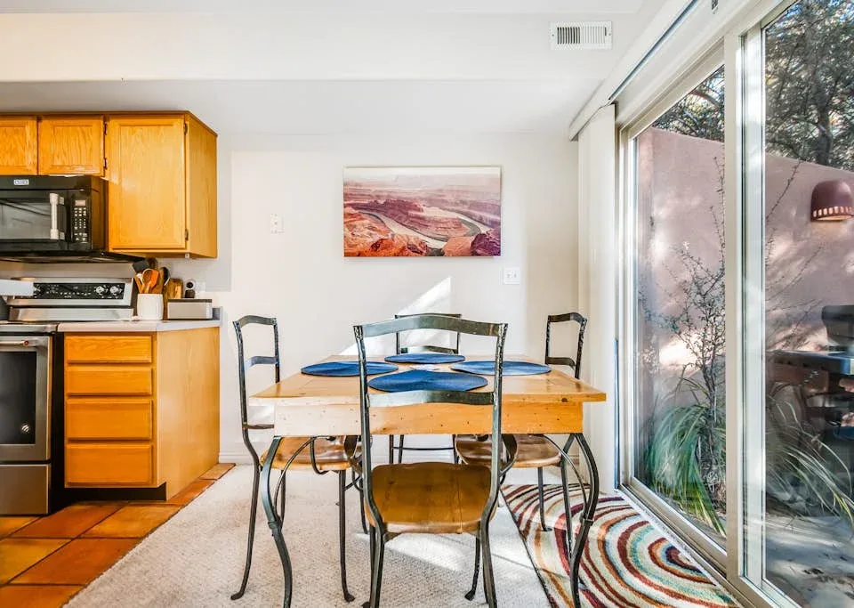 A dining area with a wooden table, chairs, and large glass doors.