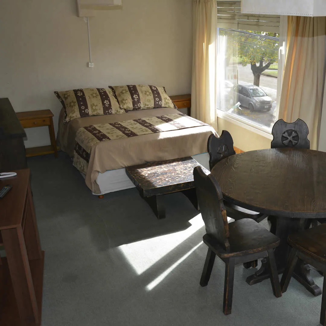 Espacio representativo del hotel: Un dormitorio con una cama y una mesa redonda junto a la ventana.