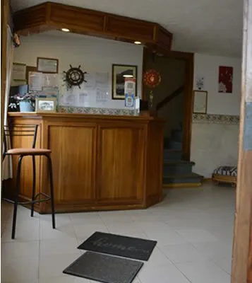 Espacio representativo del hotel: Un mostrador de recepción está junto a una escalera en un pequeño vestíbulo.