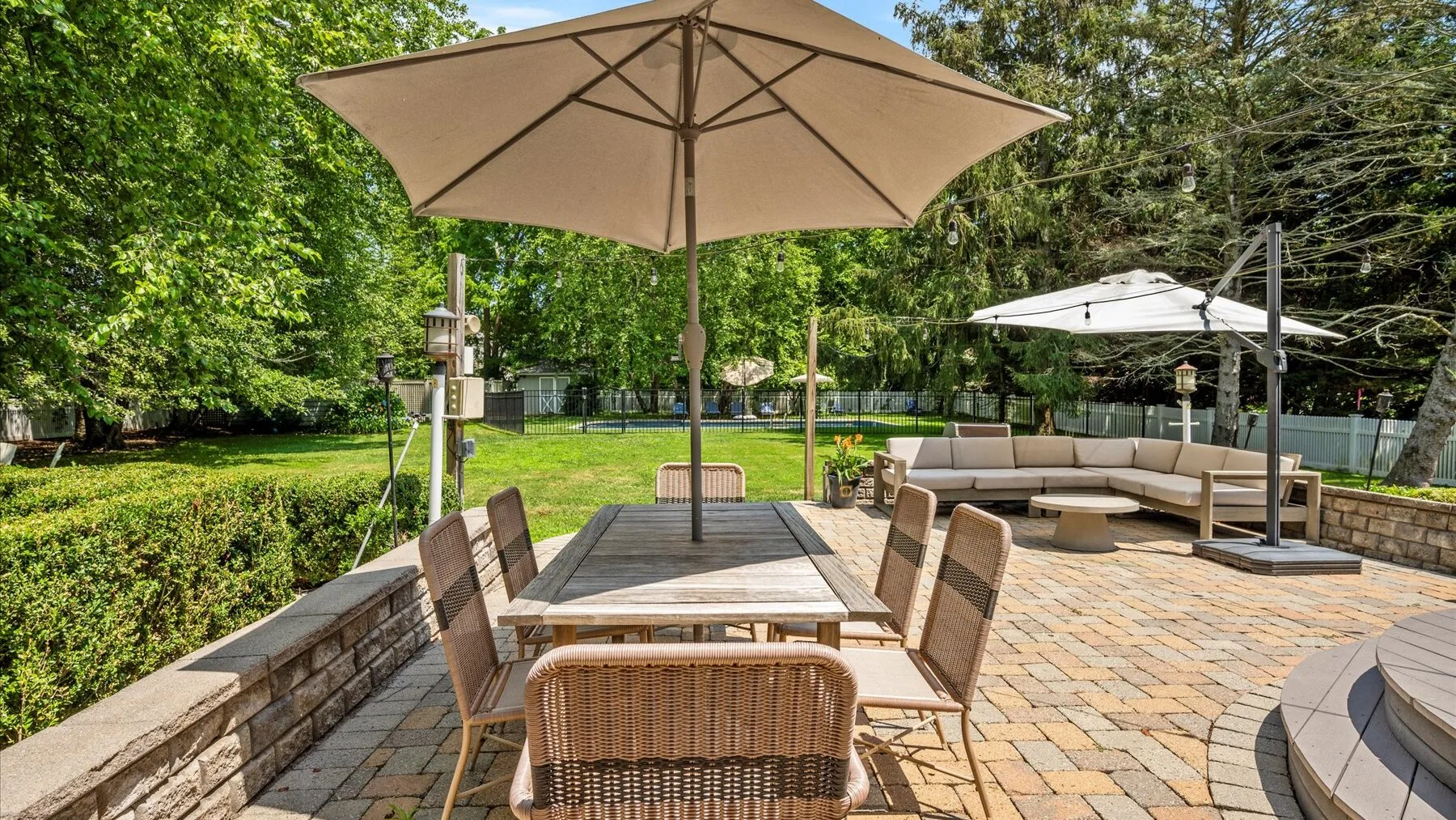 An outdoor patio with a dining table, seating, and large umbrellas.