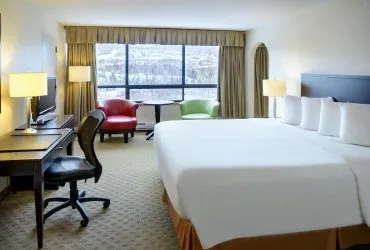 Representative hotel space: A hotel guest room has a large bed, a desk, and a seating area by the window.