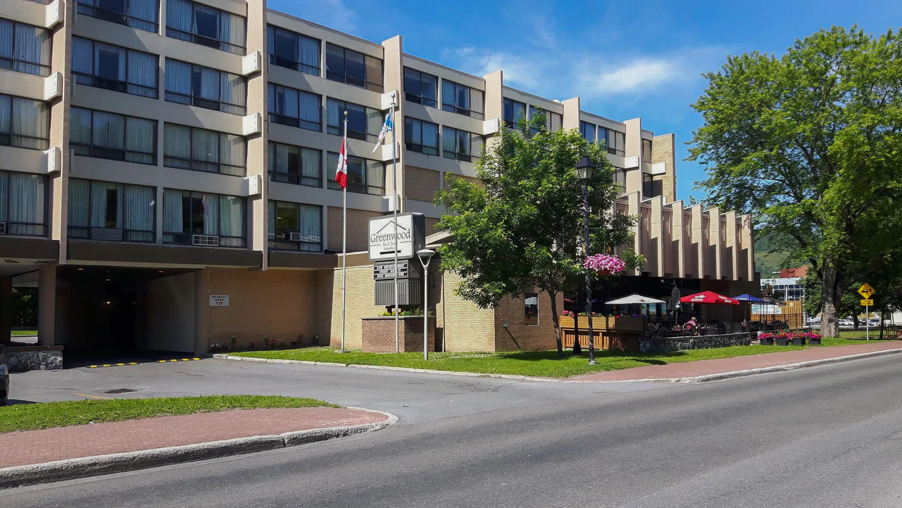 Representative hotel space: A multi-story hotel building fronts a street beside a landscaped outdoor seating area.