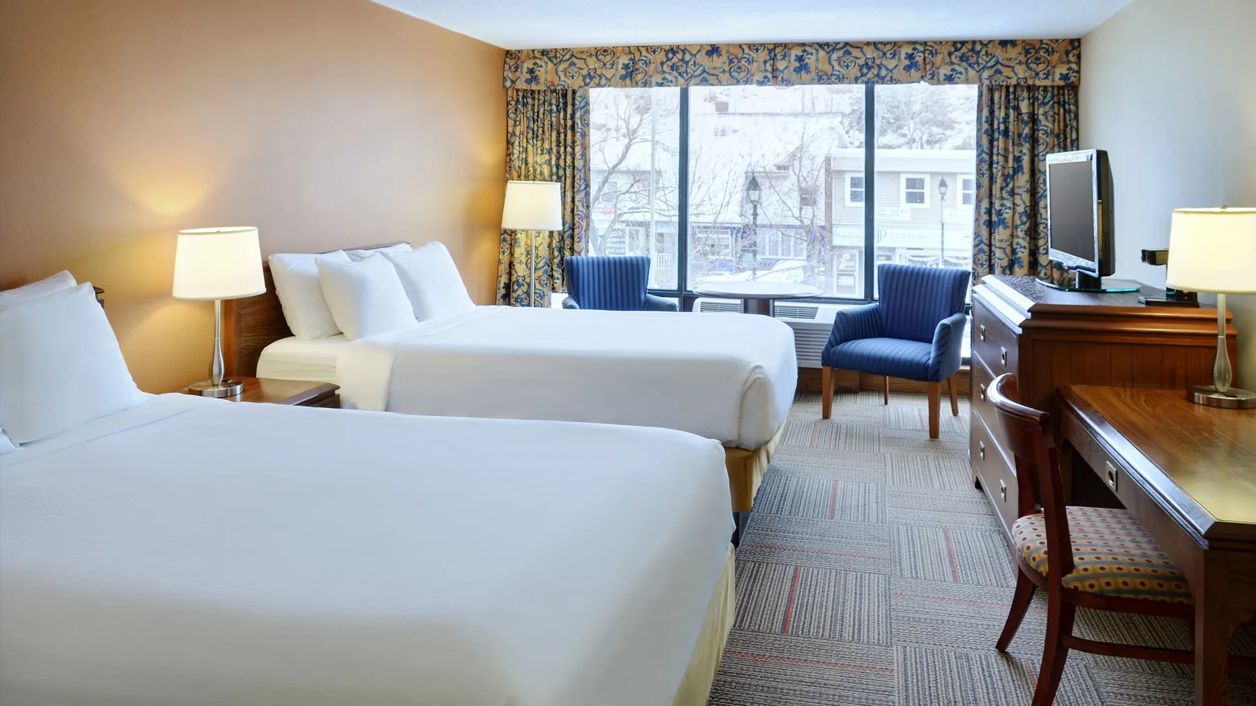 Representative hotel space: A hotel bedroom with two beds, a desk, and a large window.