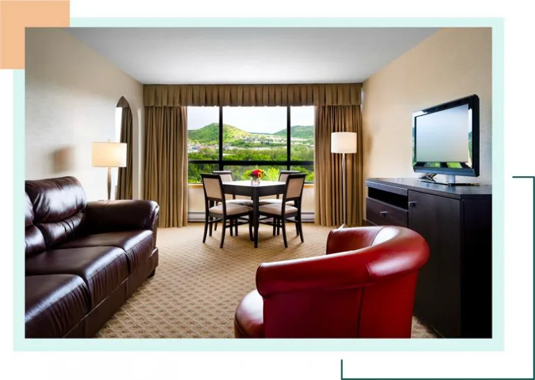Representative hotel space: A hotel living area with seating, a dining table, and a large window.