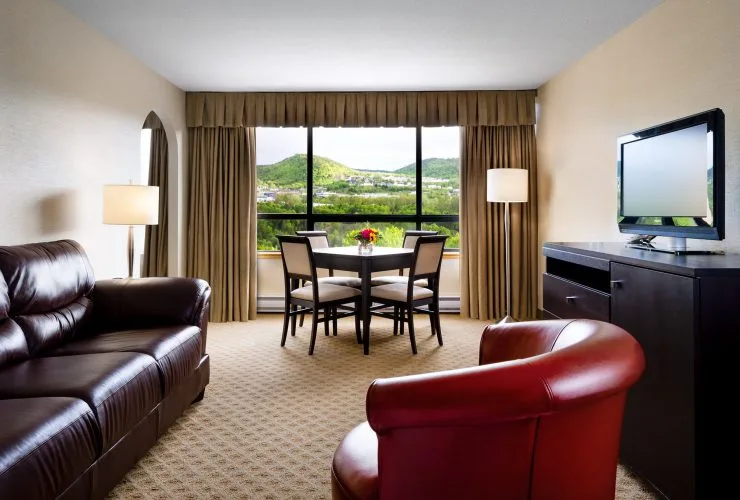 Representative hotel space: A hotel sitting area with seating, a dining table, and a window overlooking green hills.