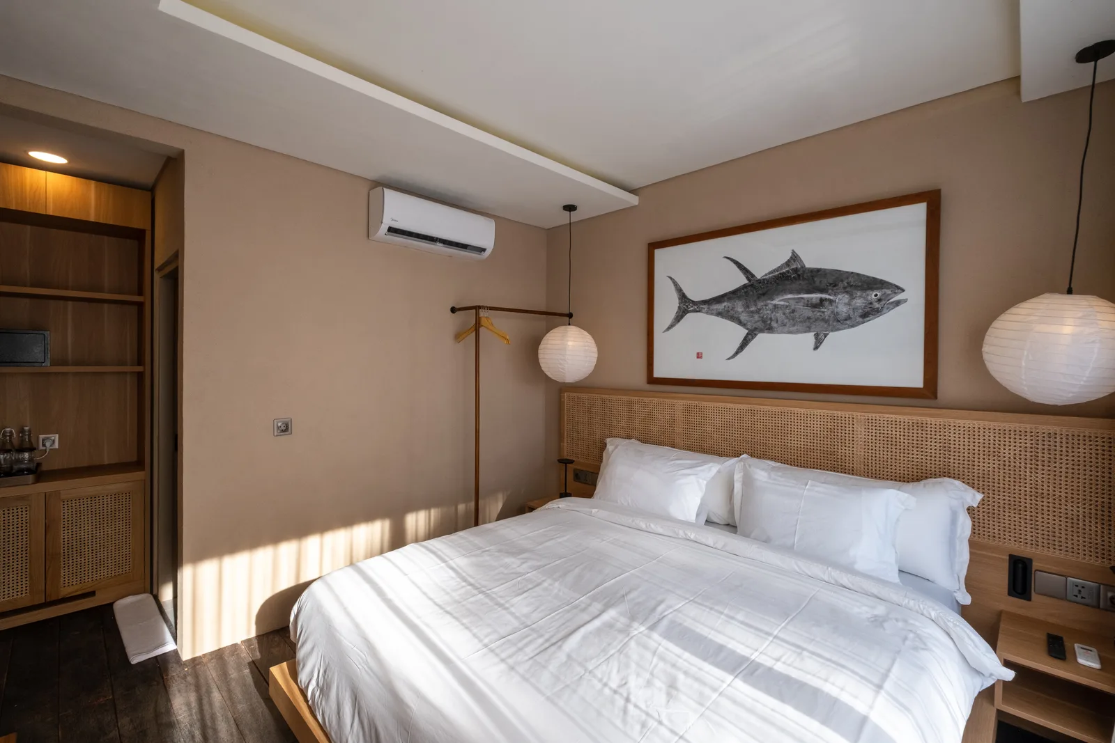 Un dormitorio con una cama bien tendida bajo un cuadro de peces.