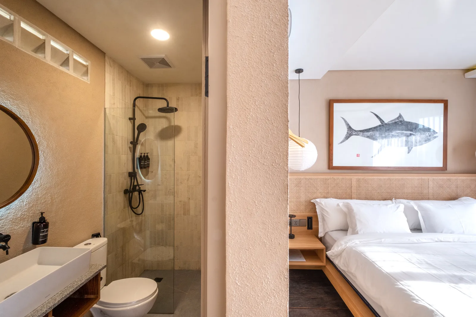 Un dormitorio con una cama bien arreglada y un baño contiguo con ducha.