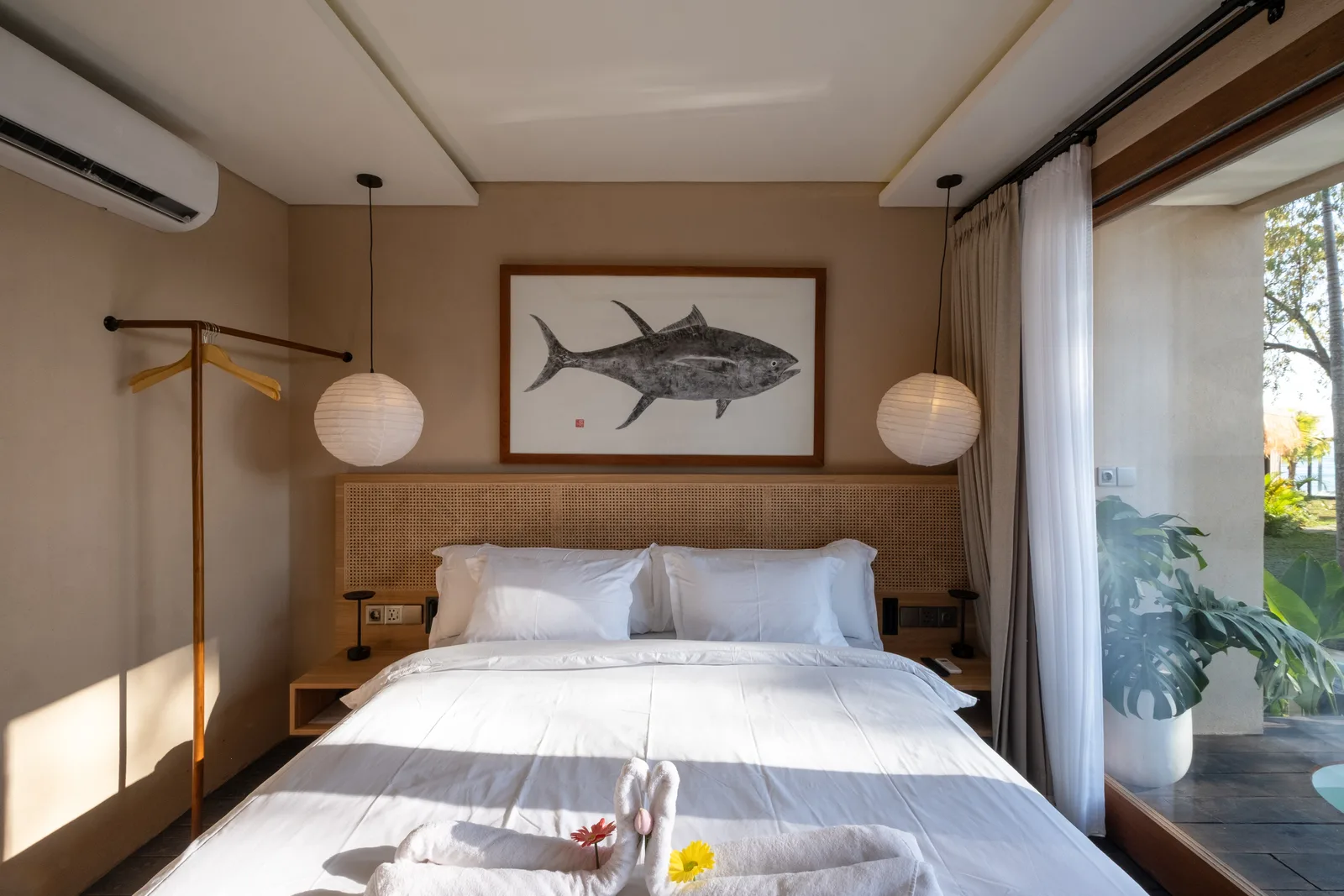 Un dormitorio con una cama bajo un cuadro de un pez y luces colgantes.