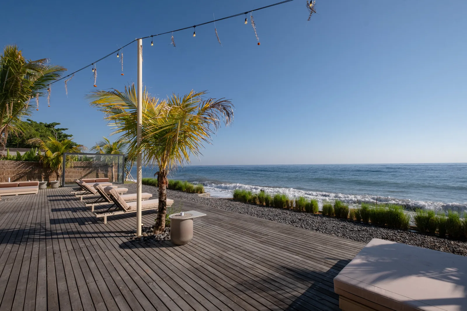 Zona común: Una terraza junto al mar con asientos, palmeras y vistas al océano.