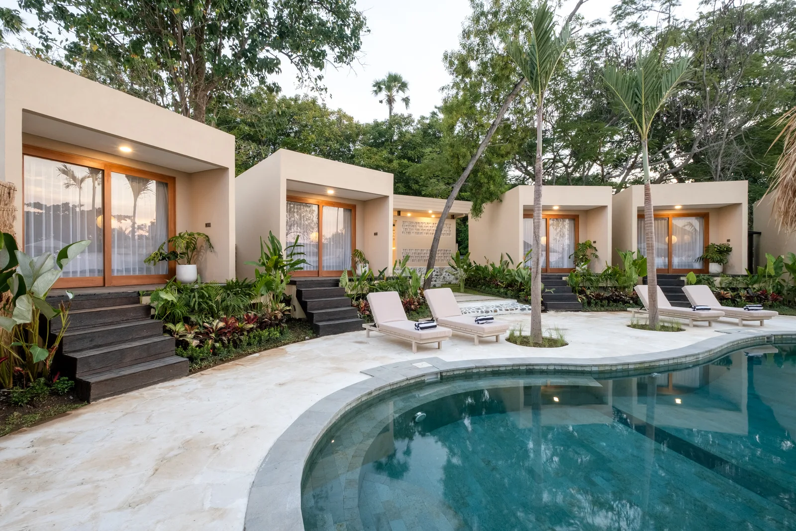 Zona común: Una piscina curva junto a varias habitaciones modernas y asientos de descanso.