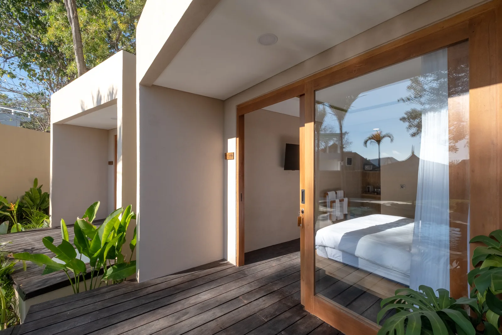 Un dormitorio se abre a una terraza de madera a través de una gran puerta de vidrio.
