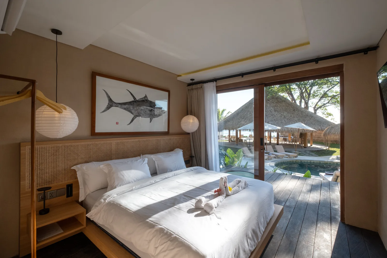 Un dormitorio con una cama tendida junto a puertas corredizas de vidrio que dan a la piscina.