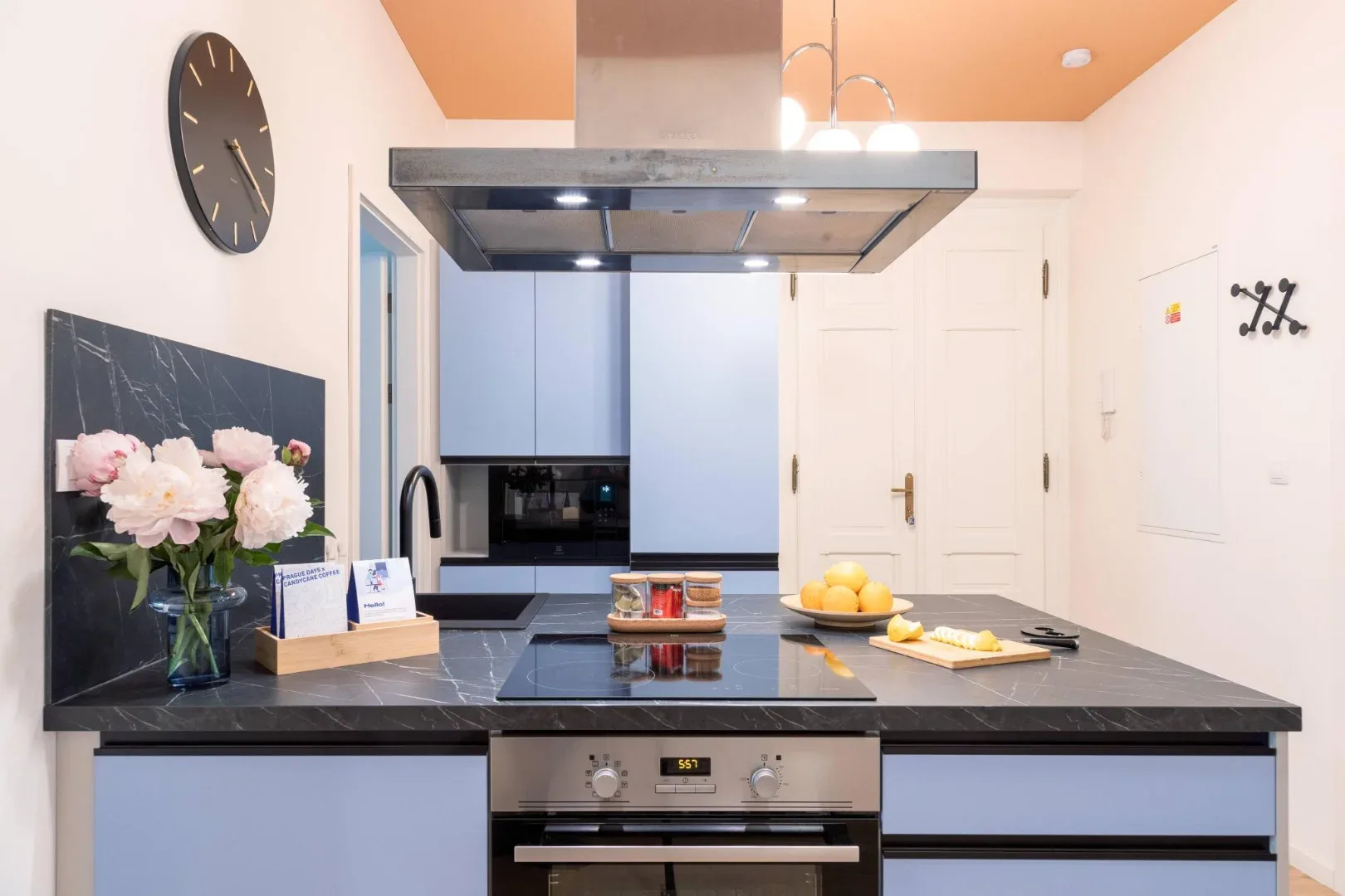 A modern kitchen with a dark stone island, built-in oven, and pale cabinets.
