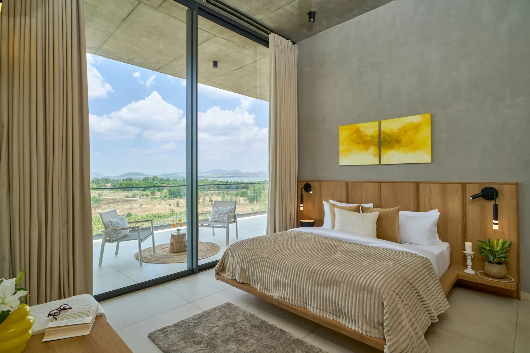 Dormitorio con una cama junto a ventanales que dan a un patio y al paisaje.