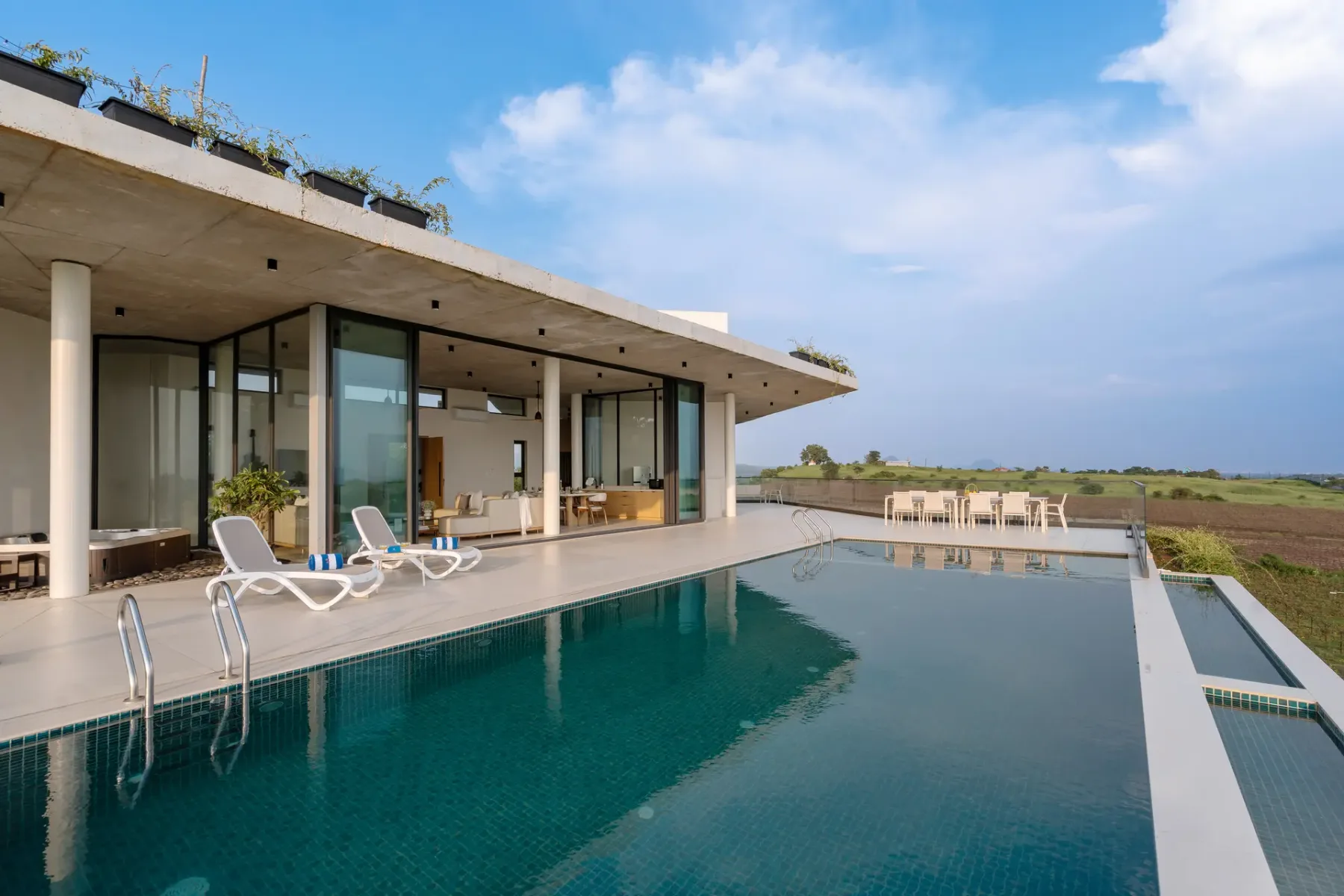 Una casa moderna se abre a una piscina con asientos para descansar.