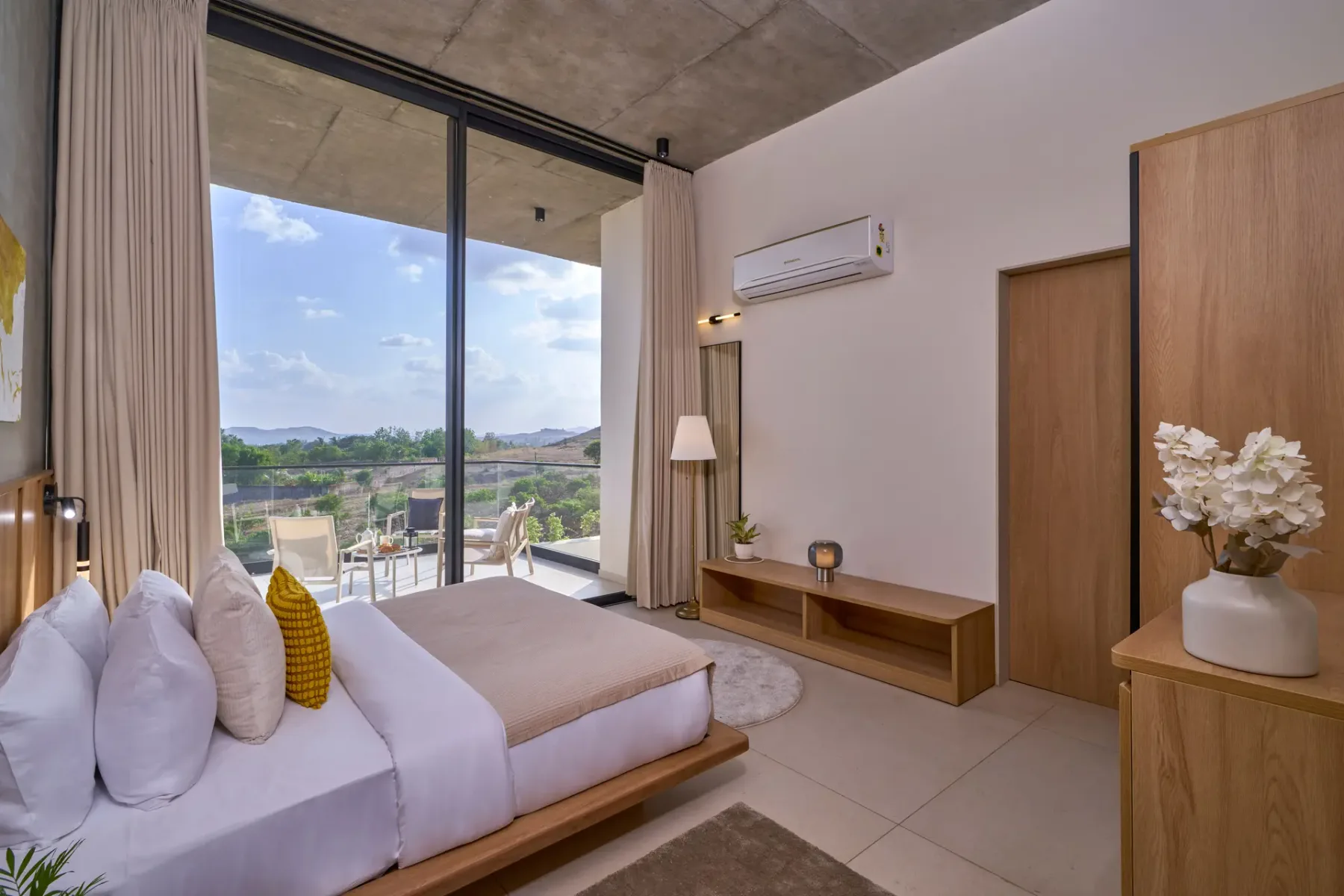 Un dormitorio con una cama junto a grandes ventanas con vistas al paisaje.