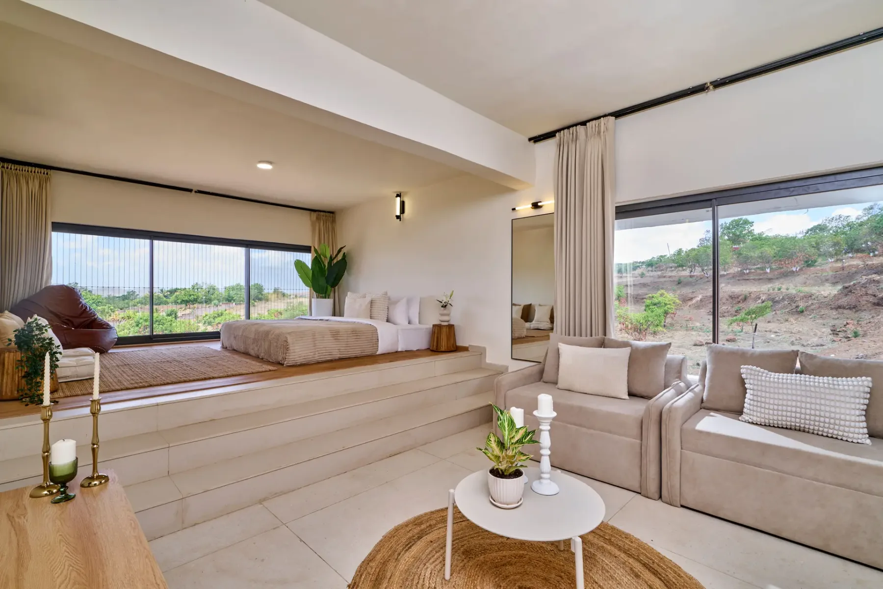 Una sala luminosa con una zona de descanso elevada y grandes ventanas con vistas a la vegetación.