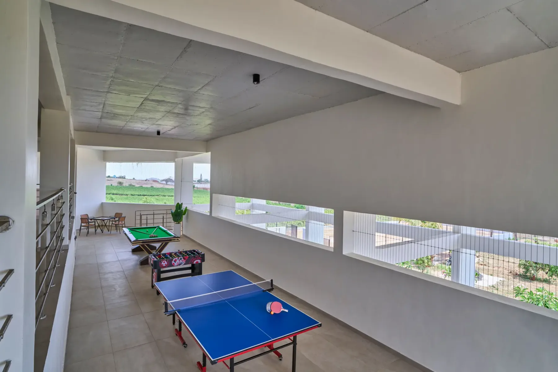 Una zona recreativa cubierta tiene una mesa de ping-pong azul y una mesa de futbolín.