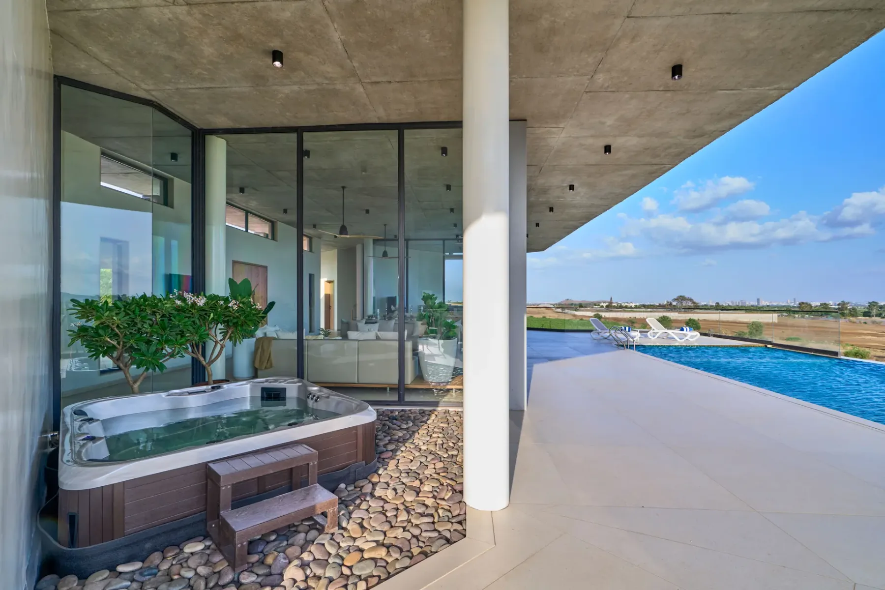 Un patio cubierto con una bañera de hidromasaje junto a una piscina.