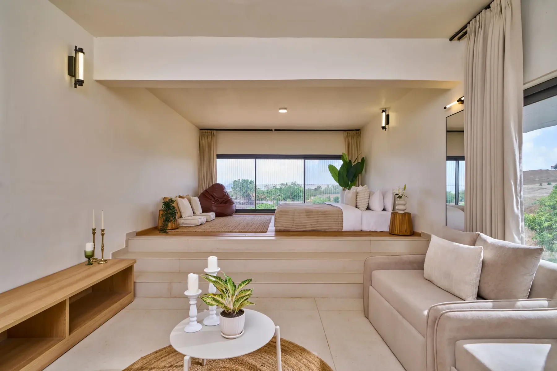 Una sala luminosa con asientos elevados junto a la ventana y un sofá cerca de ventanales.