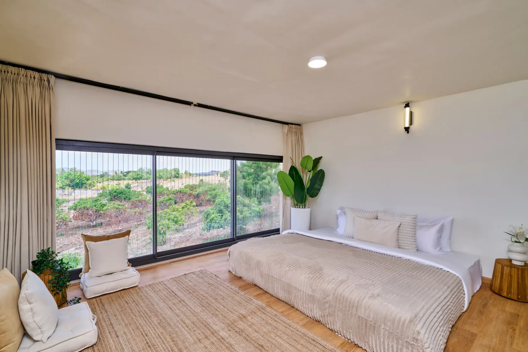 Un dormitorio con una cama junto a grandes ventanales que dan a la vegetación.