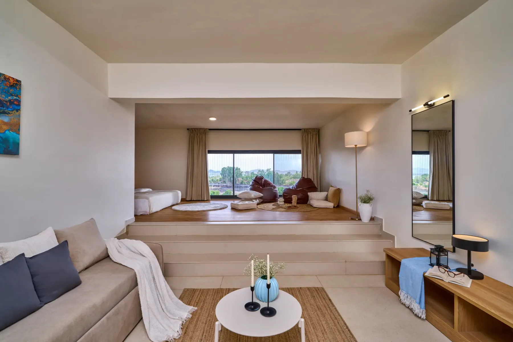 Una luminosa sala de estar con sofá, zona elevada para sentarse y grandes ventanas.