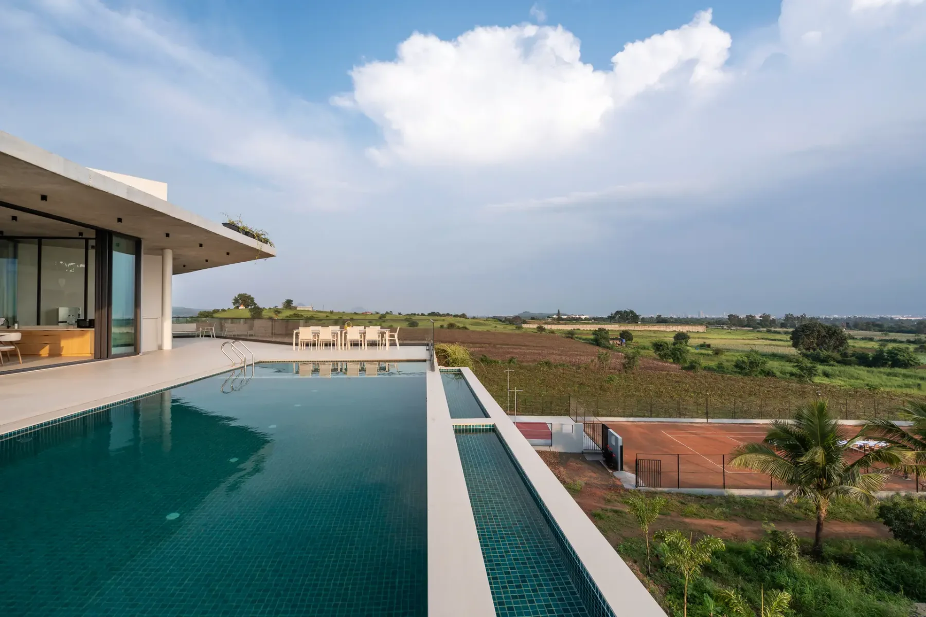 Una casa moderna junto a una piscina larga con vistas a campos abiertos.
