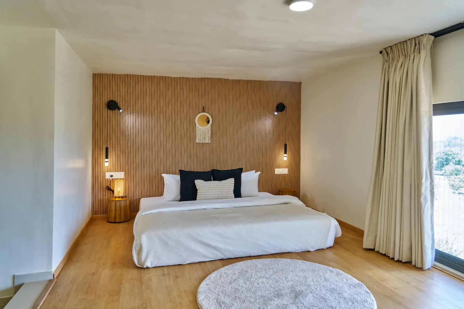 Un dormitorio con una cama tendida frente a una pared revestida de madera.