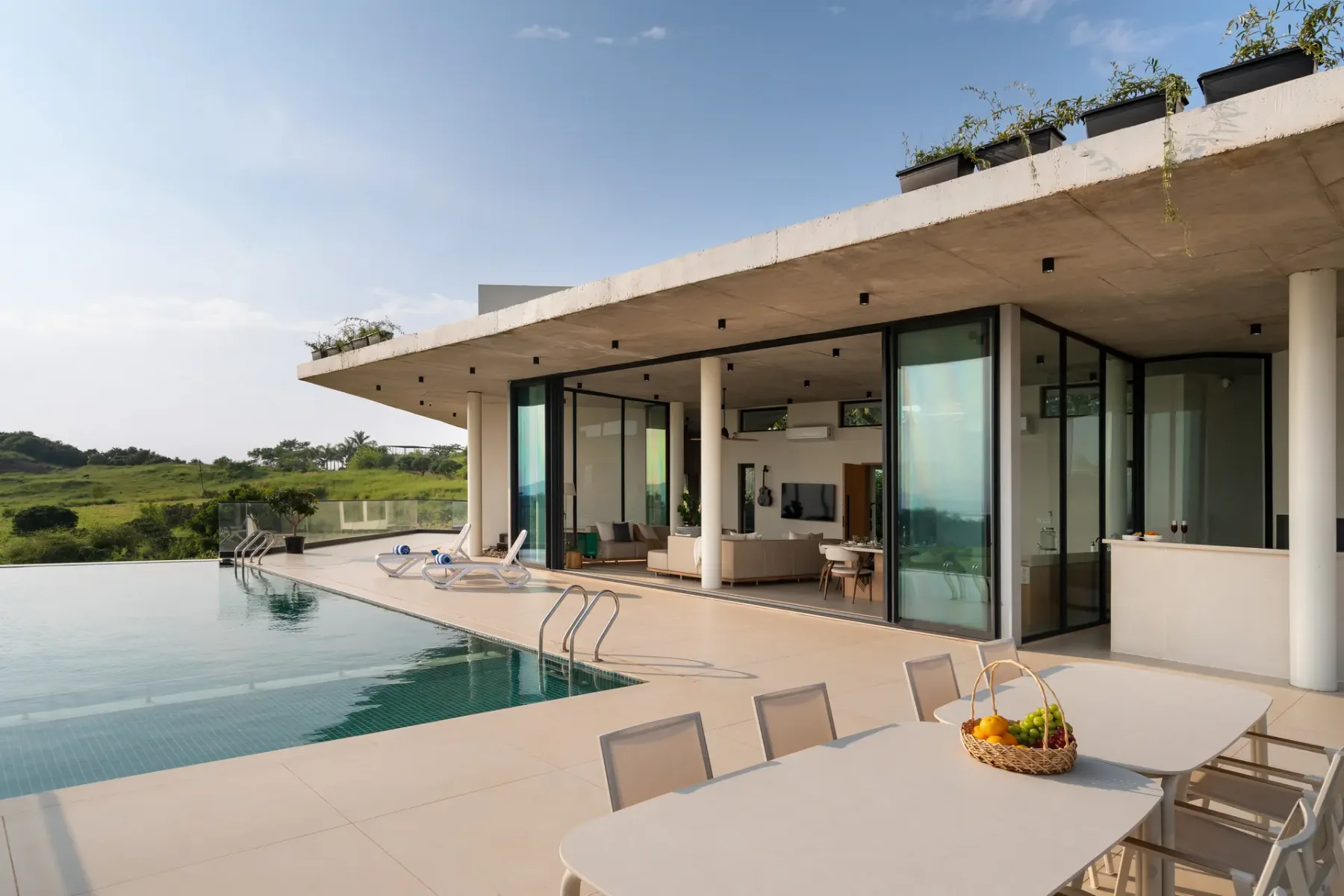 Una casa moderna se abre a una piscina y una zona de comedor al aire libre.
