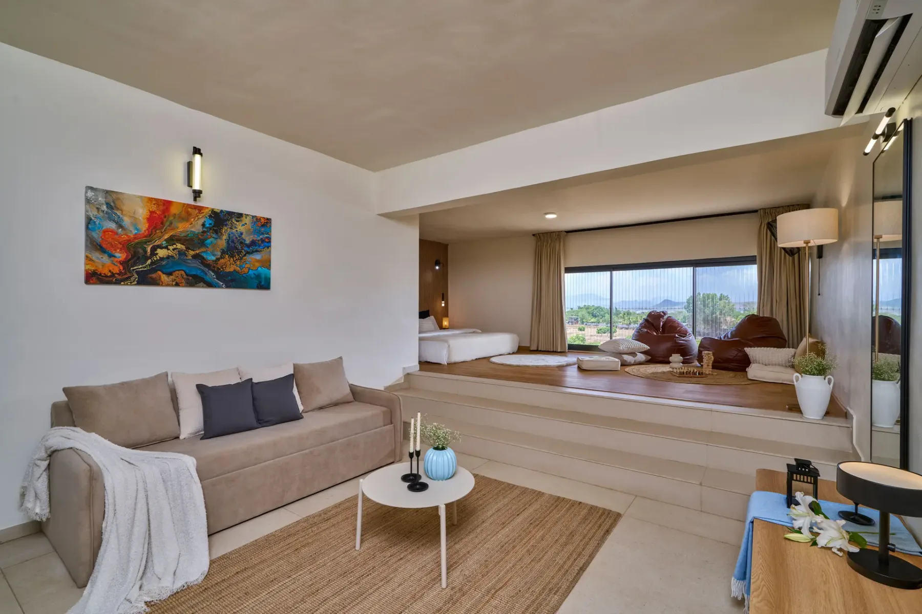 Una sala de estar con sofá y una zona elevada junto a grandes ventanales.
