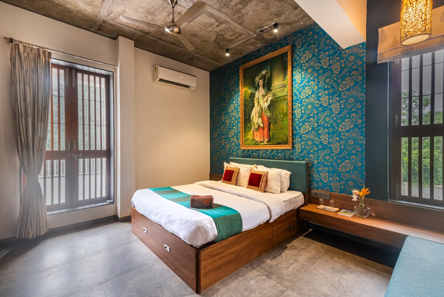 A bedroom with a wooden bed, blue patterned wall, and large framed painting.
