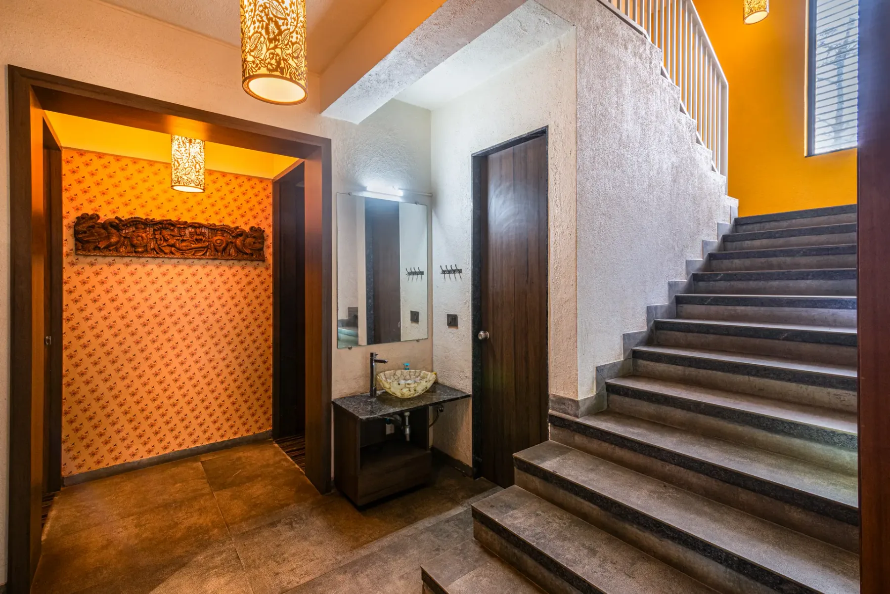 An interior stairway rises beside an orange-lit entry alcove.