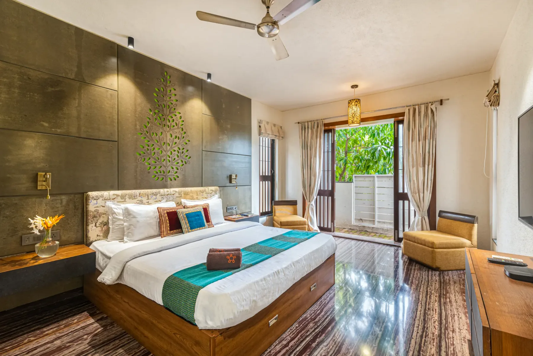 A bedroom with a large bed, bedside tables, and sliding glass doors opening to greenery.
