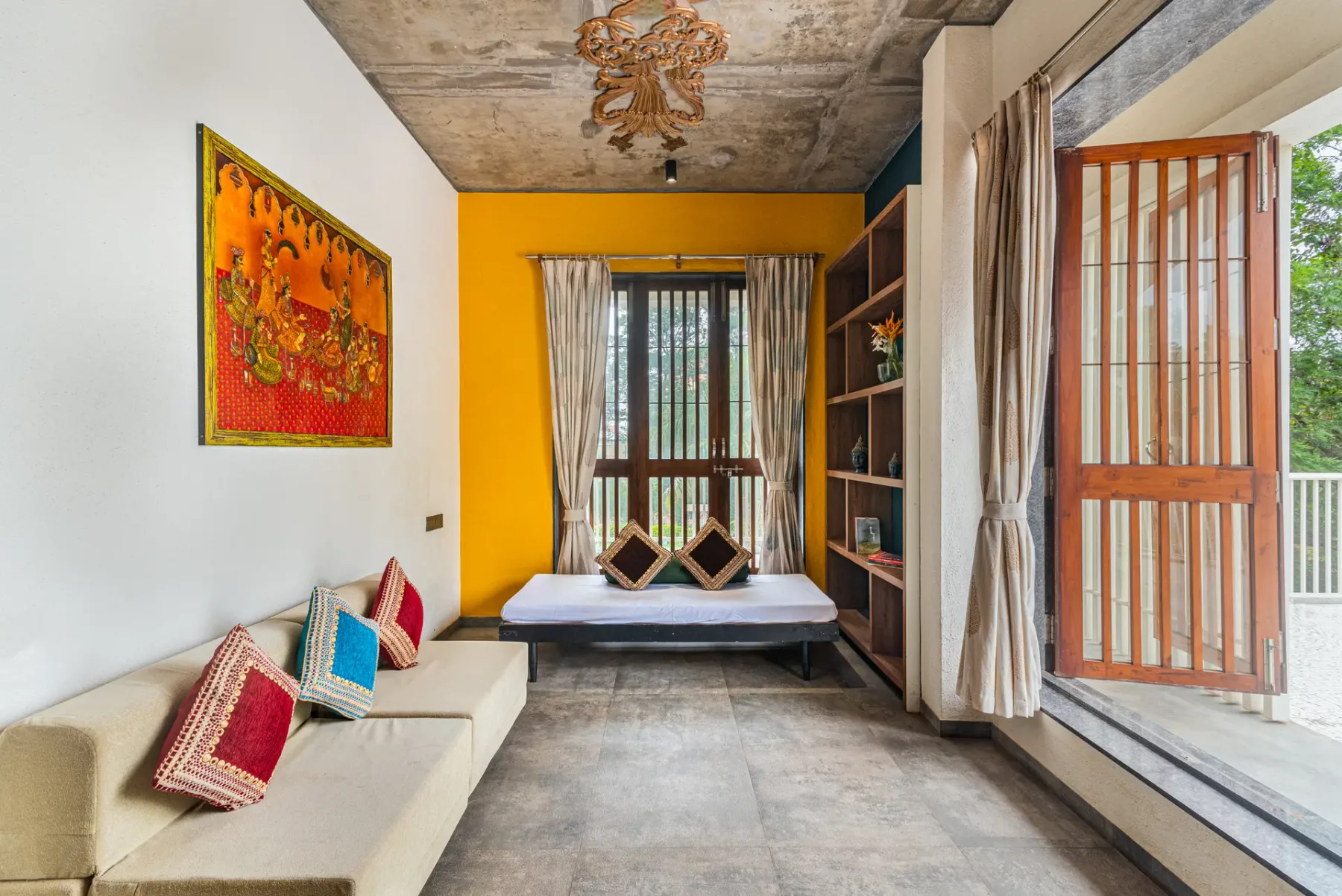 A colorful sitting room with a cushioned bench and a daybed by the window.
