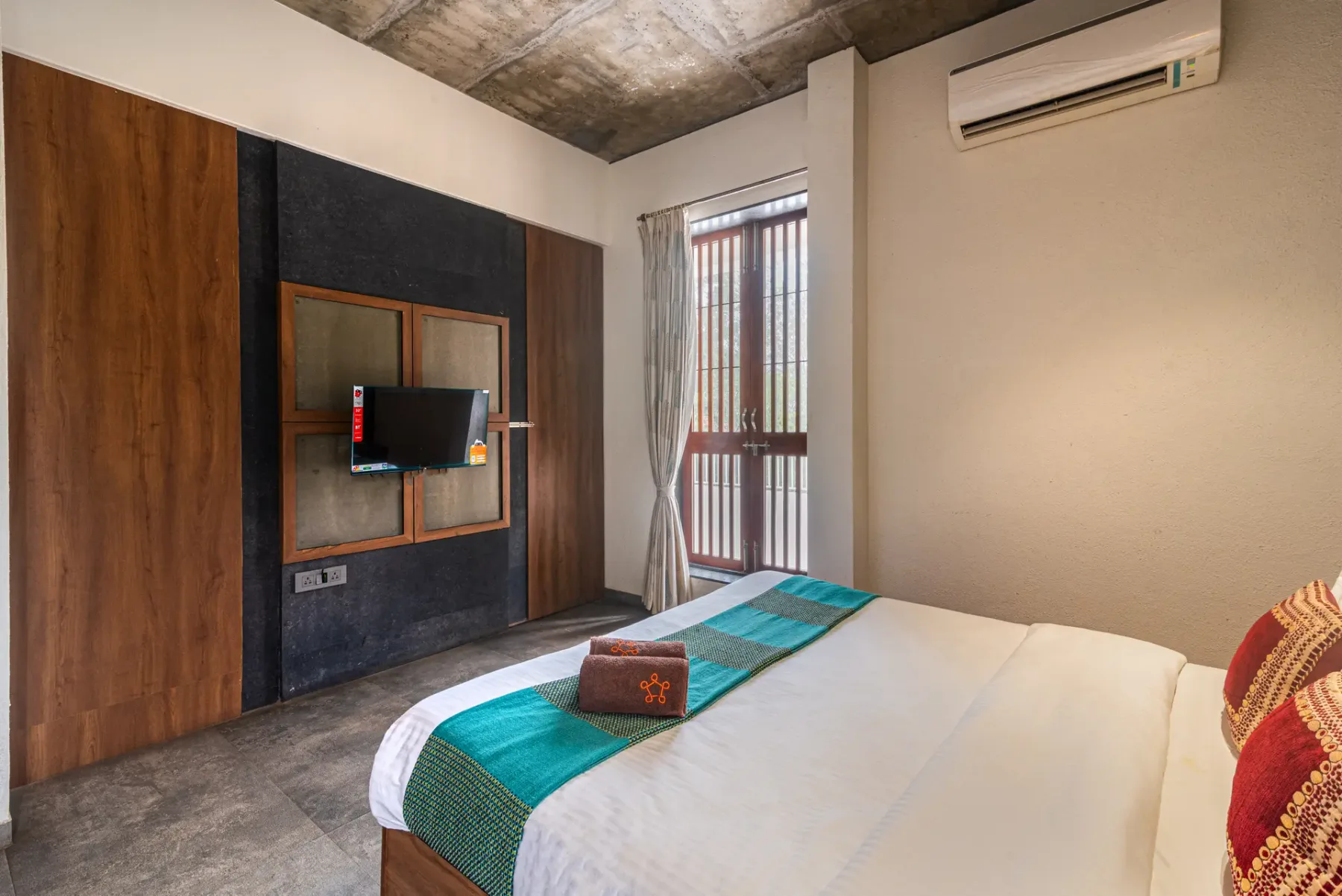 Bedroom with a bed, a wall-mounted television, and a tall barred window.