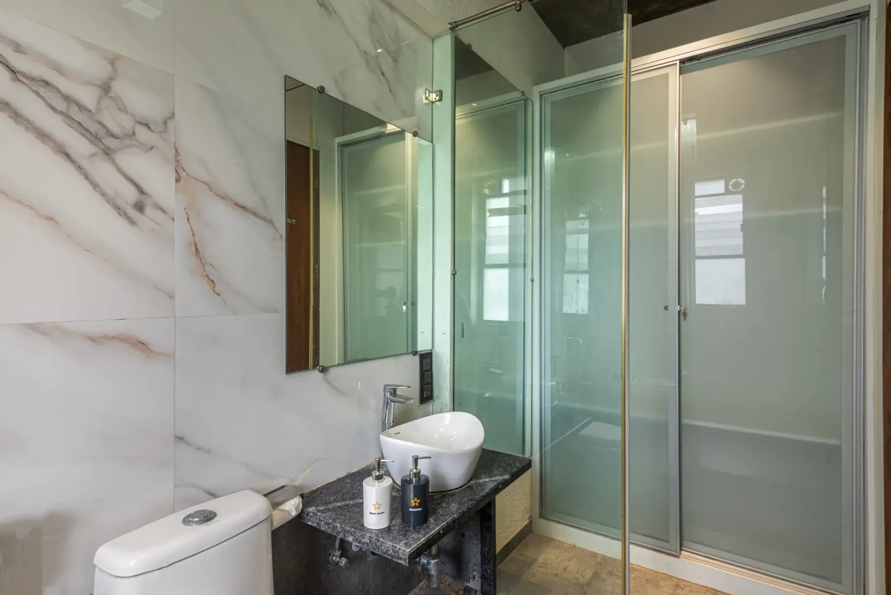 A tiled bathroom with a vessel sink and glass shower enclosure.
