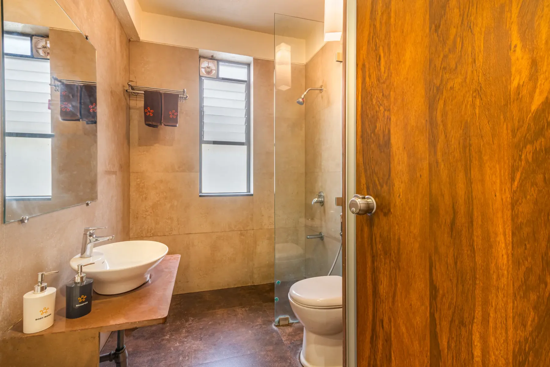 A bathroom with a vessel sink, window, shower, and toilet.