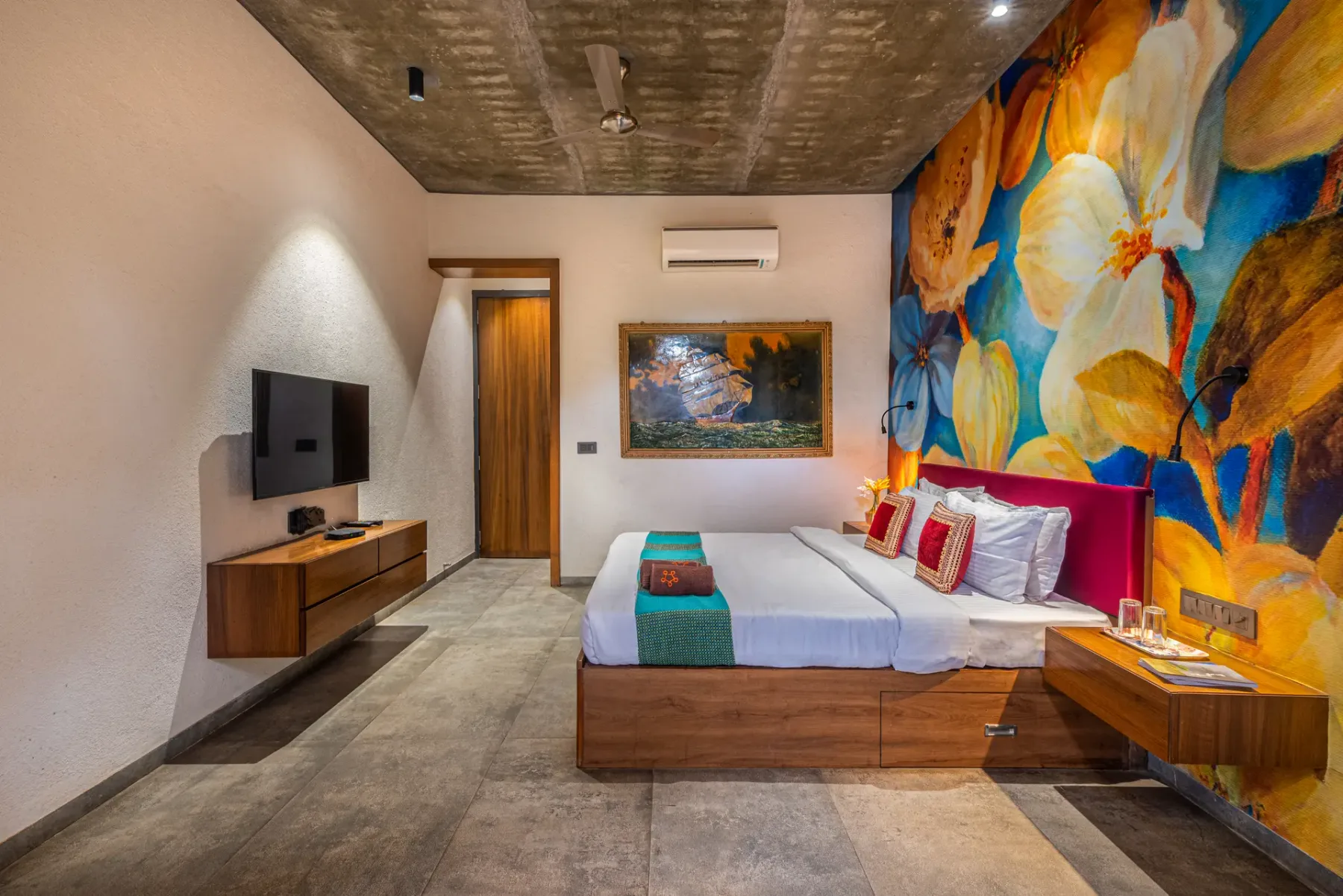 A bedroom with a bed beside a colorful floral wall mural.