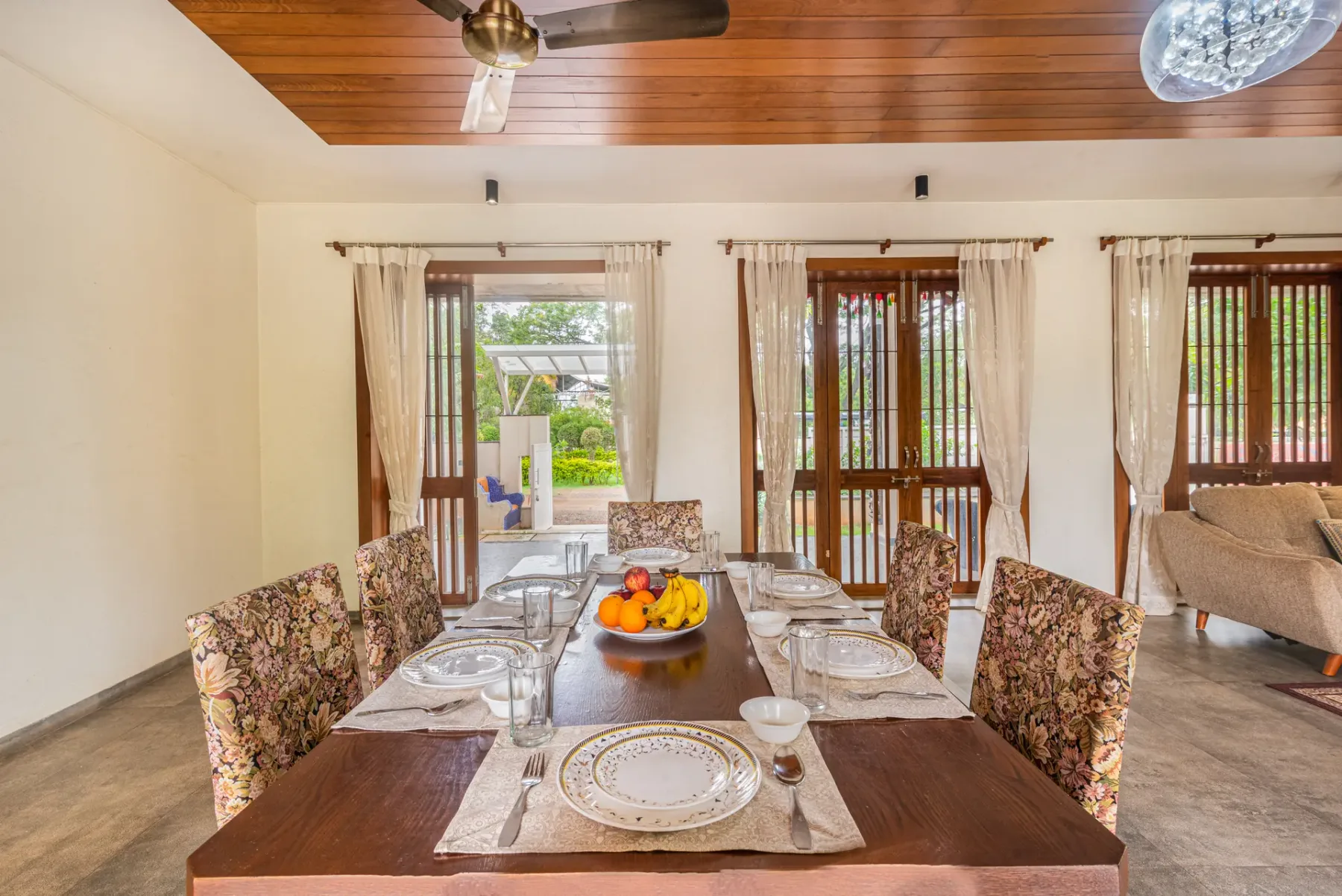A dining area with a set table and sliding glass doors opening onto greenery.