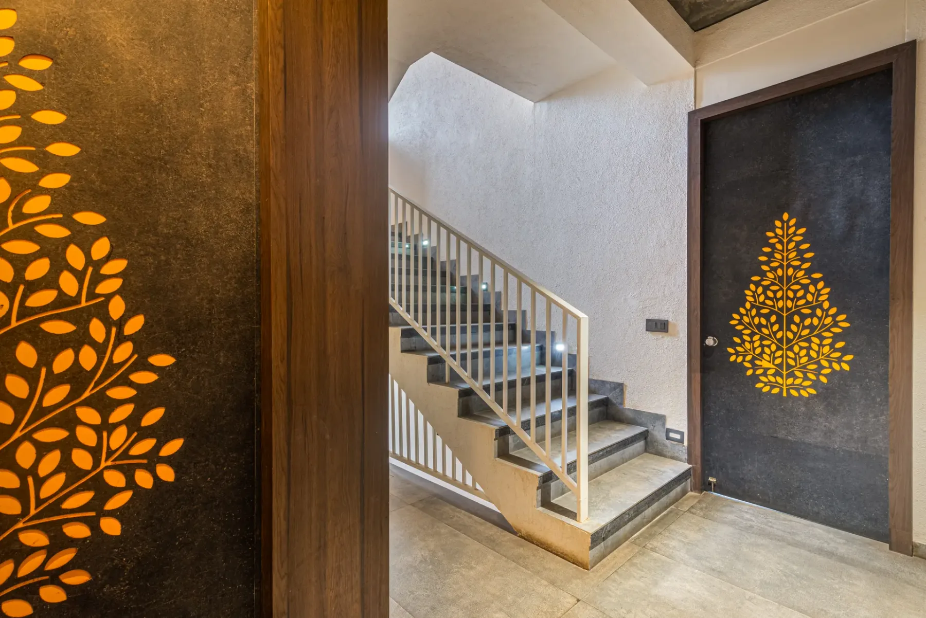 An indoor staircase with a light-colored railing beside a dark decorative door.