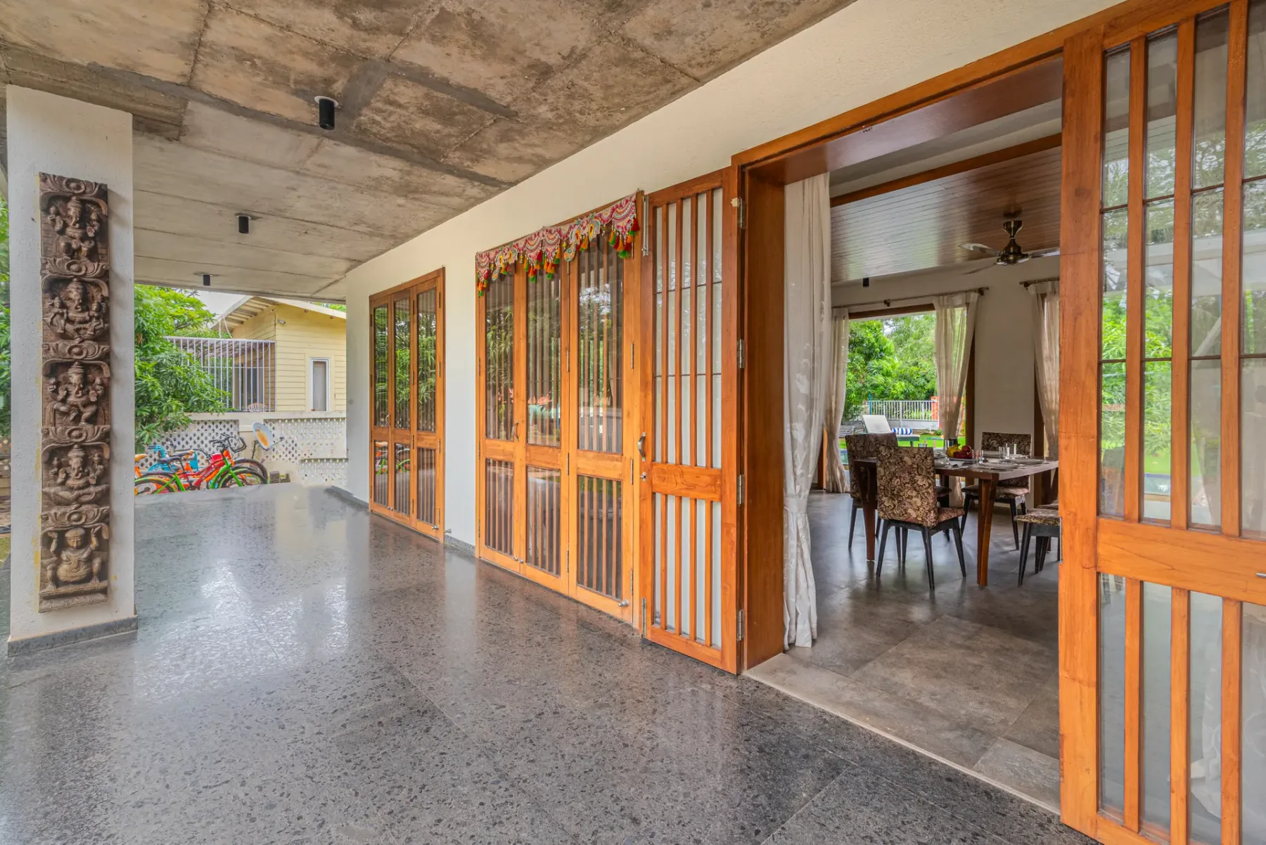 A covered patio with wooden folding doors opens onto a dining area.