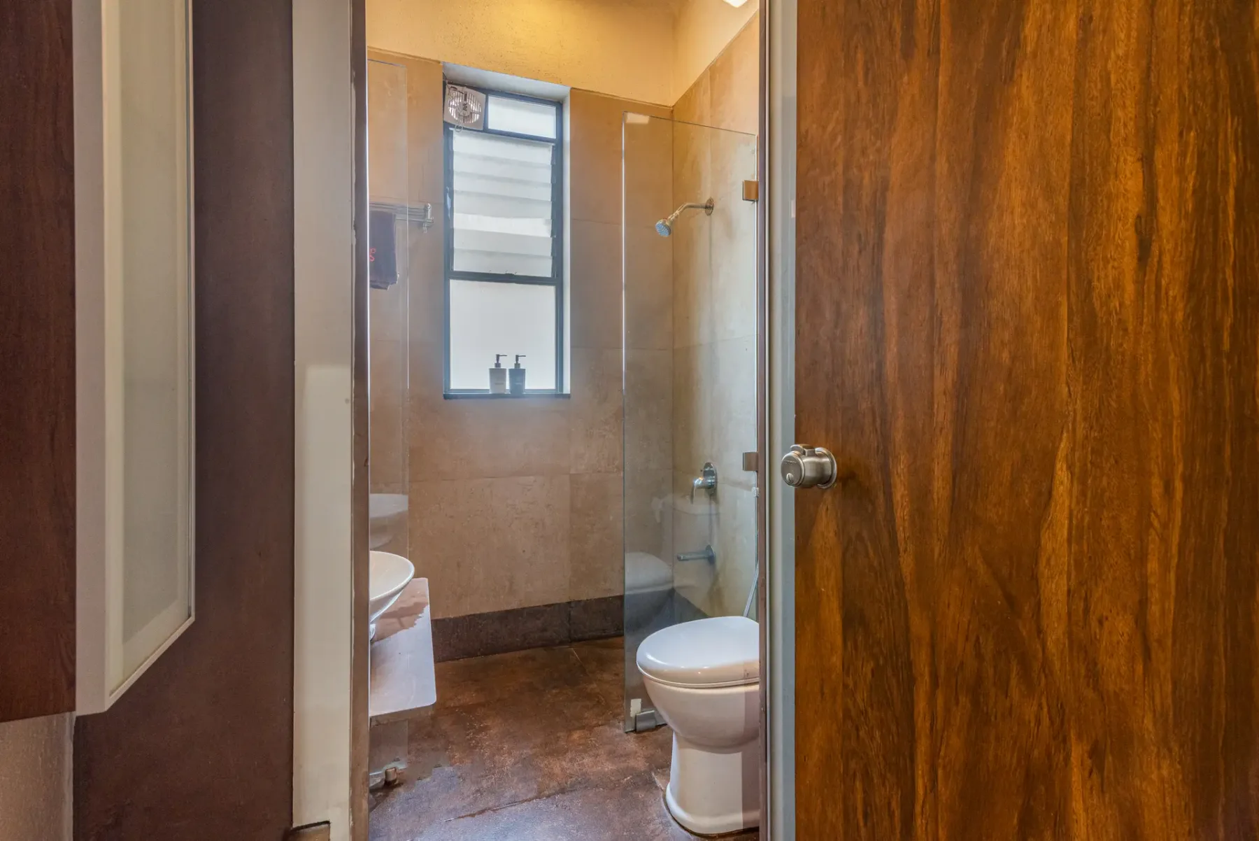 A bathroom with a window, shower, and toilet.