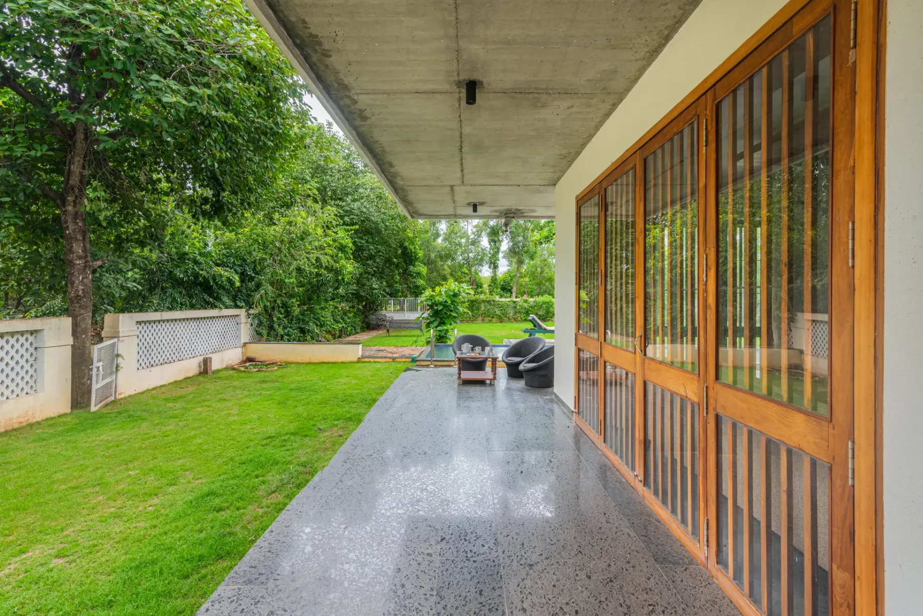 A covered patio with outdoor seating beside a garden.