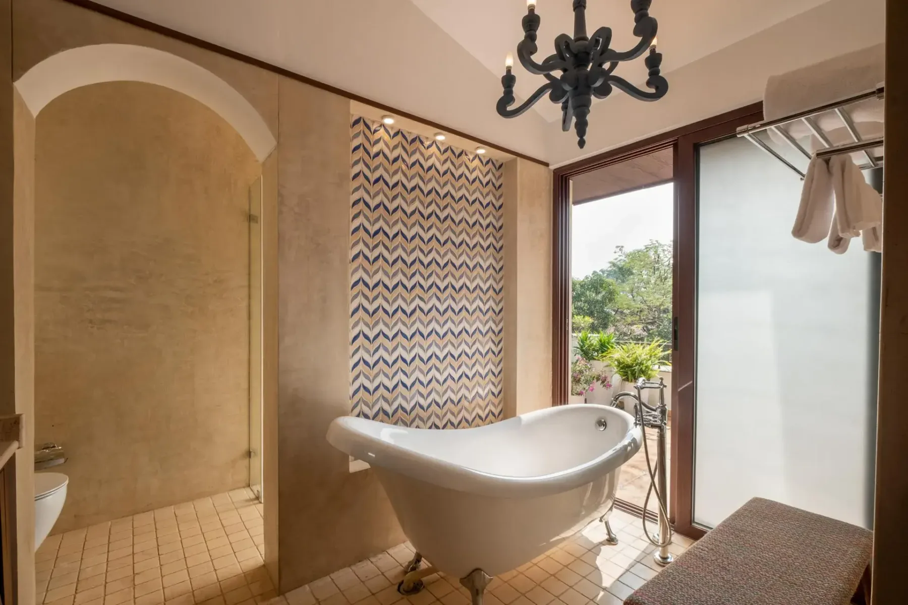 A freestanding bathtub sits beside a glass shower and a tall window overlooking greenery.