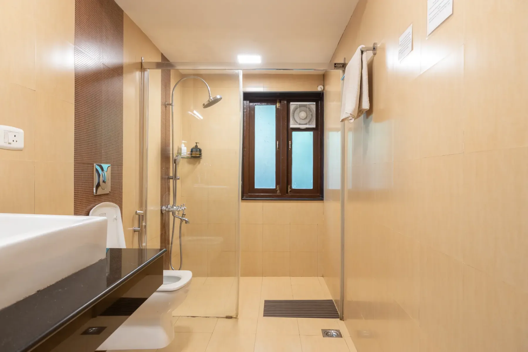 Un baño con ducha de vidrio, lavabo y ventana.